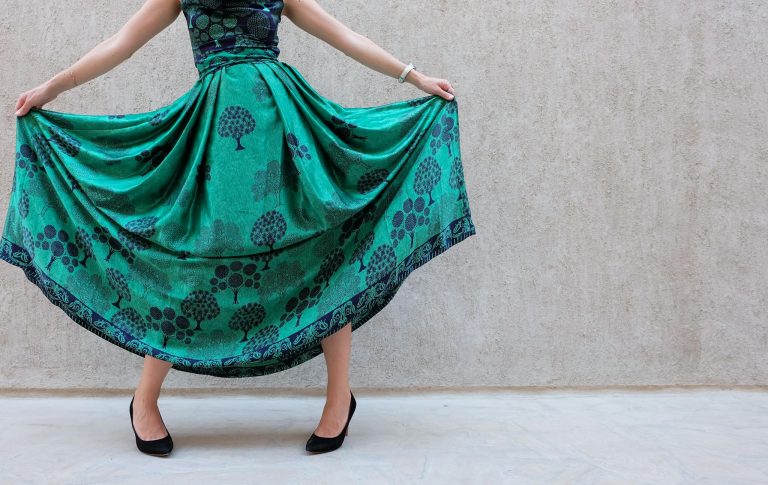 A stylish woman poses with a green patterned skirt, showcasing elegance and fashion.