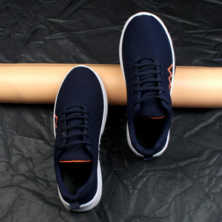 Stylish navy blue sneakers with white soles and laces placed on a textured dark backdrop.